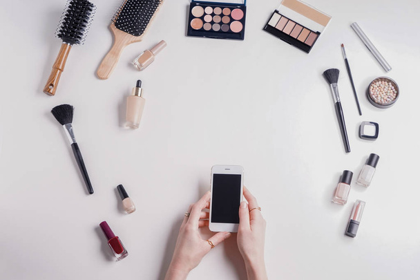 携帯電話と白い背景の上の化粧品美容ブロガー - 写真・画像