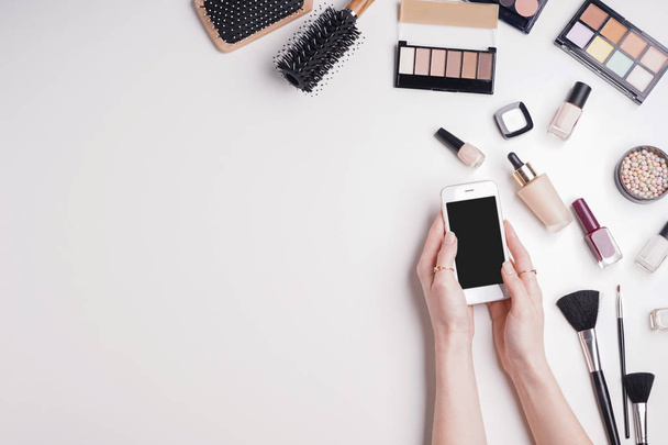 Blogueur beauté avec téléphone portable et cosmétiques de maquillage sur fond blanc
 - Photo, image