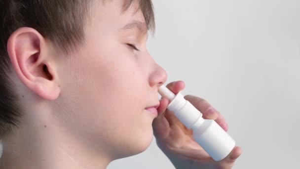 Chłopiec przy użyciu aerozolu do nosa i uśmiechając się - Materiał filmowy, wideo