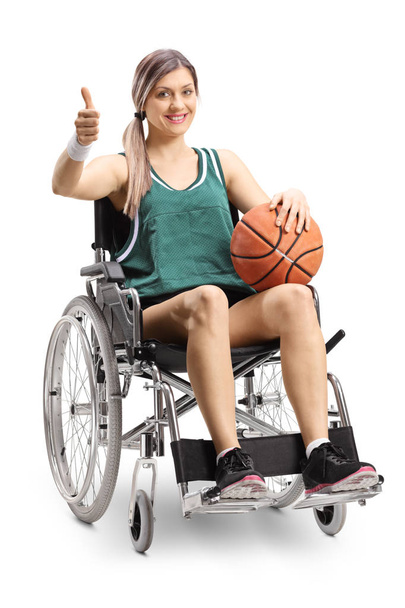 Młodych kobiet sportowiec na wózku inwalidzkim, trzymając koszykówki i Wyświetlono kciuki do góry na białym tle na białym tle - Zdjęcie, obraz