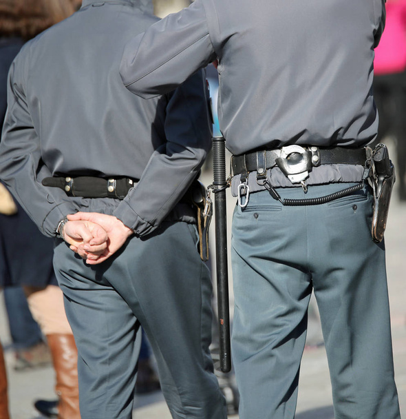 двое полицейских патрулируют с наручниками и коляской во время патрулирования по улицам города
 - Фото, изображение