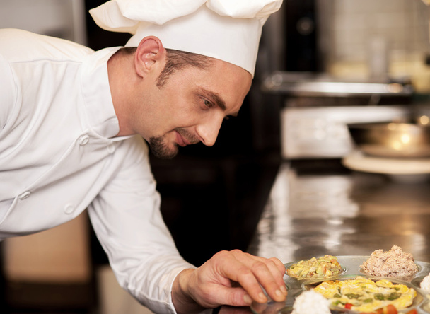 Satisfied chef analyzing dish before serving - Foto, Imagen
