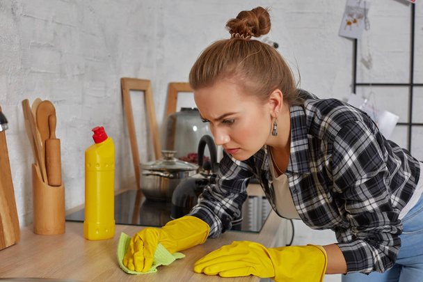 El temizliği. Genç ev hanımı mutfakta lavabo yıkıyor. Elle yıkanan genç bir kadın, sarı temizleme eldiveni giyiyor.. - Fotoğraf, Görsel