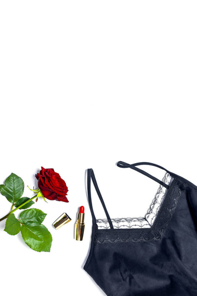 weibliche schwarze T-Shirt-Jacke mit Spitze, rotem Lippenstift und Rosenblüten auf weißem Hintergrund von oben flach liegend. Beauty Fashion Hintergrund. sexy Klamotten, modischer Look, Frauenurlaub - Foto, Bild