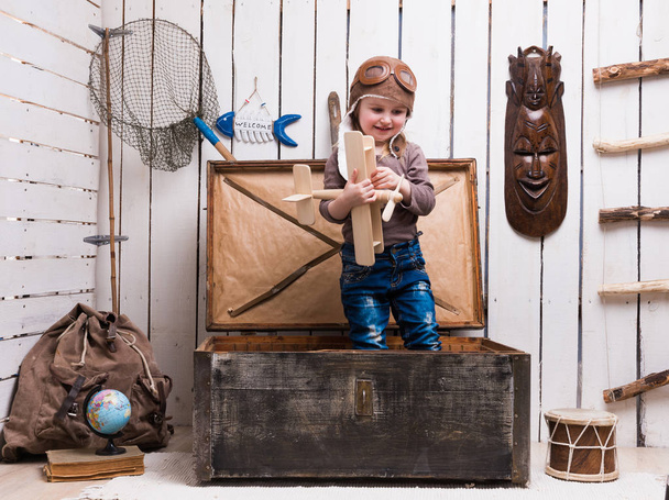 little girl in chest with wooden plane in hands - Фото, изображение