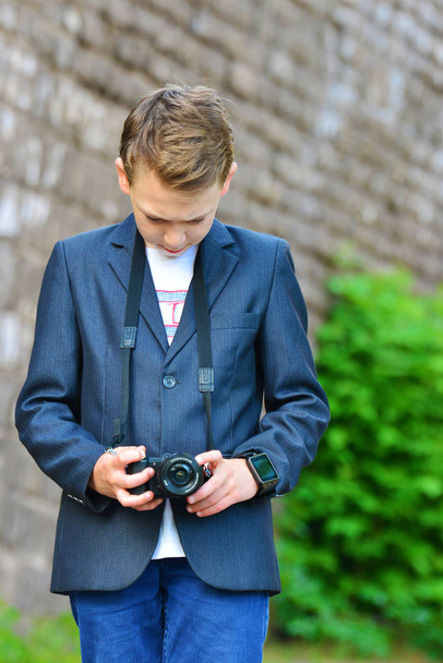 Egy fiú az utcán kamerával nézi a fotó után a kép. - Fotó, kép