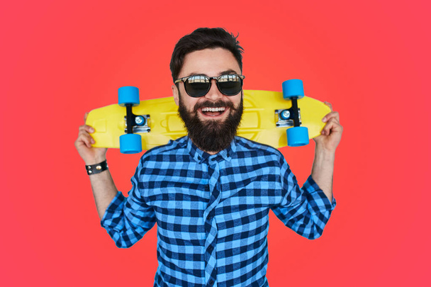 Bearded hipster in sunglasses holding longboard  - Photo, Image
