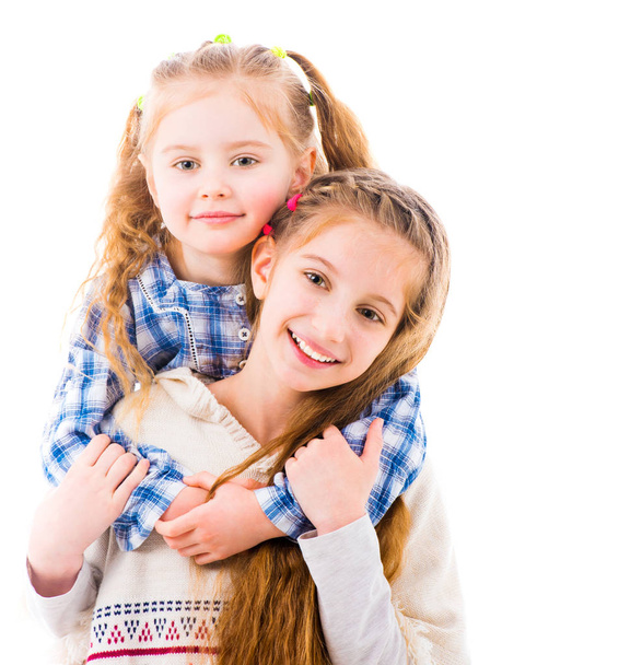 Две маленькие девочки в повседневной одежде обнимаются
 - Фото, изображение