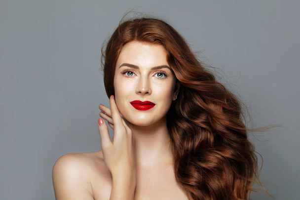 Kırmızı kıvırcık saçlı güzel kadın. Neşeli Kızıl saçlı model mavi renkli portre üzerinde - Fotoğraf, Görsel
