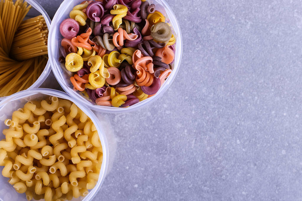 Multicolored pasta with the addition of natural vegetable dye. In jar on a concrete table. Top view, copy Space. - Foto, afbeelding