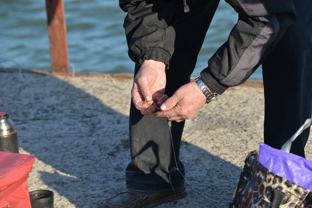 A man is stringing a worm on a hook for fishing for a fishing rod - Photo, Image