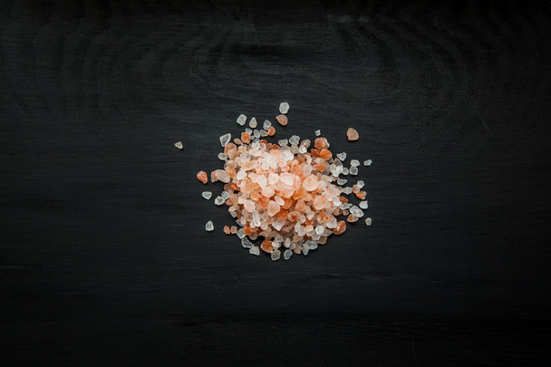 Close-up image of Himalayan salt grains on black wood background, view above - Fotografie, Obrázek