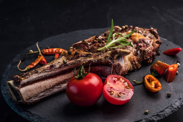 Beef steak with rosemary, chili peeper and tomatoes on slate board - Fotoğraf, Görsel