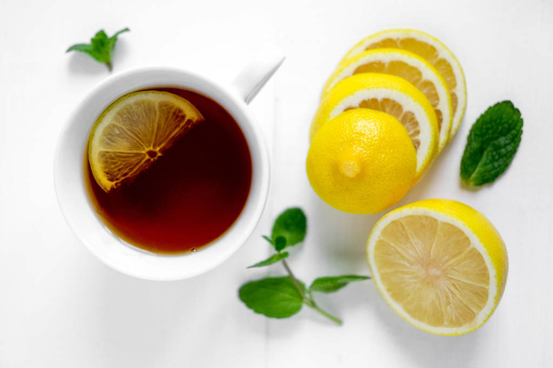 Photo of a cup of tea with lemon and mint. White cup of tea with lemon. Drink for convalescence. - Fotografie, Obrázek