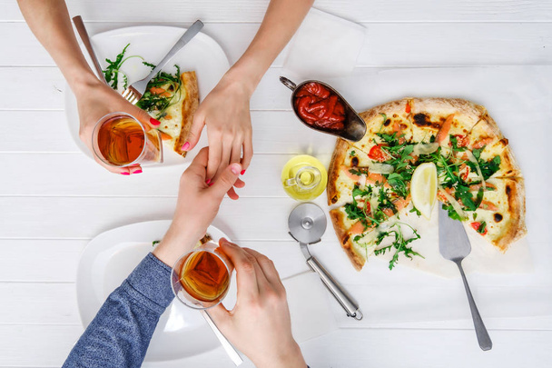 Two people shake hands while eating pizza - Fotoğraf, Görsel