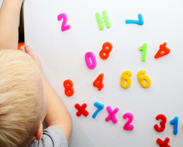 A little boy is studying the magnetic numbers on the fridge. Preschooler training - Photo, Image