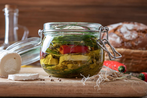 Marinating goat cheese in oil with wild crow garlic, hot peppers and coriander seeds - Fotografie, Obrázek