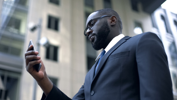 Bedrijfstoepassing, ernstige Afro-Amerikaanse zakenman werken op smartphone - Foto, afbeelding