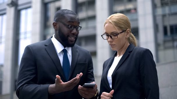 Boss showing female employee business diagrams in smartphone, new technology - Valokuva, kuva