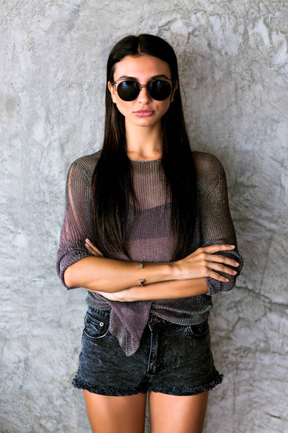 Giovane ragazza hipster posa vicino al muro grigio, vestito in stile rilassato
 - Foto, immagini