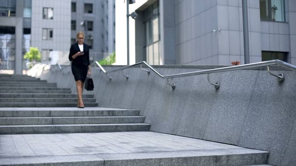 Beautiful woman walking down stairs and checking mail on smartphone, busy life - 写真・画像