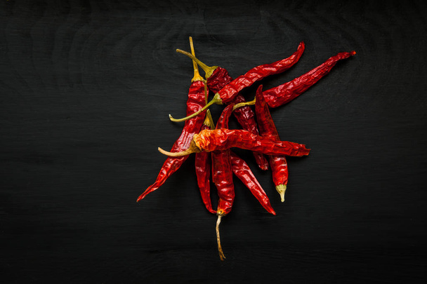 Close-up image of dry red pepper on black wood background, view above - Fotó, kép