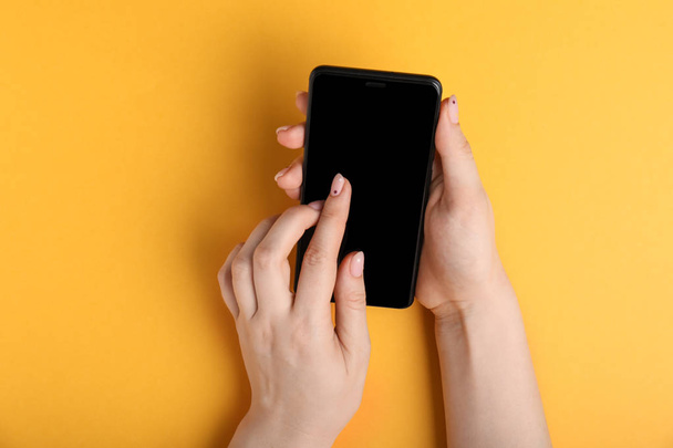 Vrouwelijke handen met manicure mobiele telefoon bedrijf op een achtergrond met kleur - Foto, afbeelding