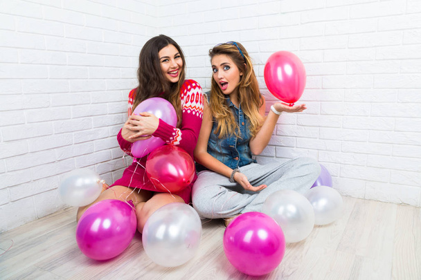 Funny positive portrait of hipsters best friends  having fun together, siting on the floor with pink balloons, happy  holidays.  - Photo, Image