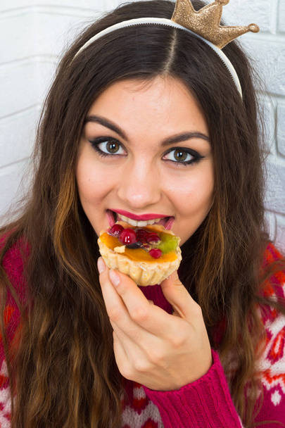 Young beautiful woman in party crown eating cake  - Photo, Image