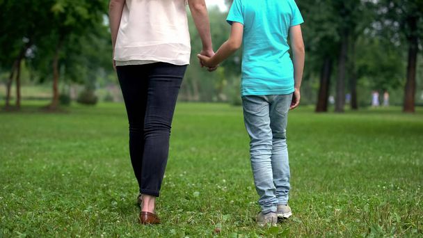 Mother and son holding hands, walking away together, concept of child adoption - Photo, Image