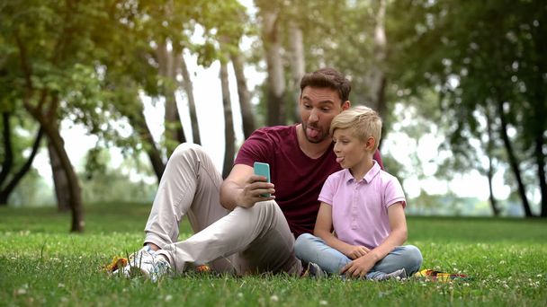 Father and child taking selfie with smartphone, capturing happy family moment - Foto, Imagem