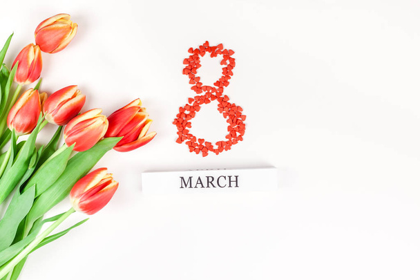 Креативний плоский вид зверху 8 березня Міжнародний жіночий день вітальна листівка з весняними квітами червоних тюльпанів на білому тлі. Шаблон святкування листівки
 - Фото, зображення