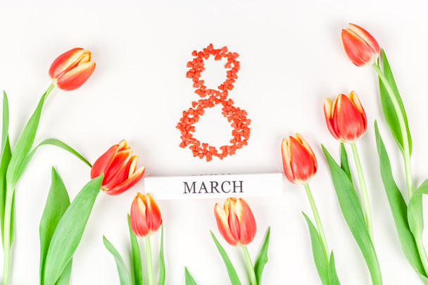 Креативний плоский вид зверху 8 березня Міжнародний жіночий день вітальна листівка з весняними квітами червоних тюльпанів на білому тлі. Шаблон святкування листівки
 - Фото, зображення