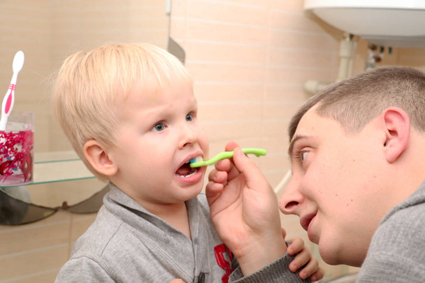 Батько і син чистити зуби у ванній кімнаті. Батько чистити зуби, щоб дитина - Фото, зображення