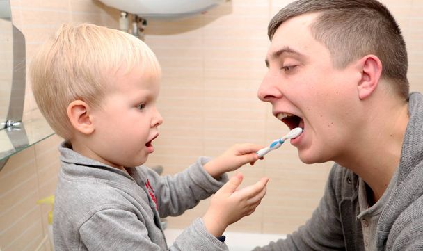 Baba ve oğul banyoda dişlerini fırçalıyorlar. Baba çocuk diş fırçalama - Fotoğraf, Görsel