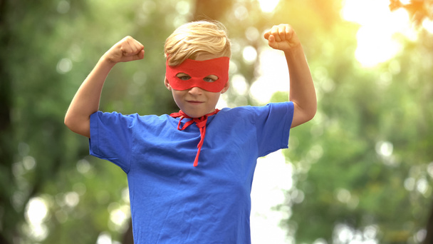 Superhero boy showing muscles, game as psychotherapy for child confidence - Фото, изображение
