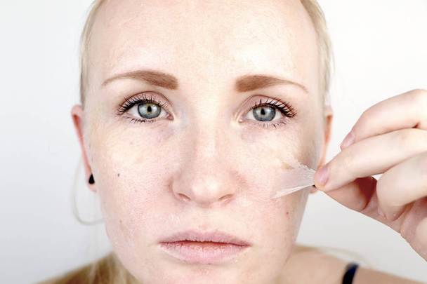 The girl removes the mask film from the face. The concept of removing old dry skin, self-care - Photo, Image
