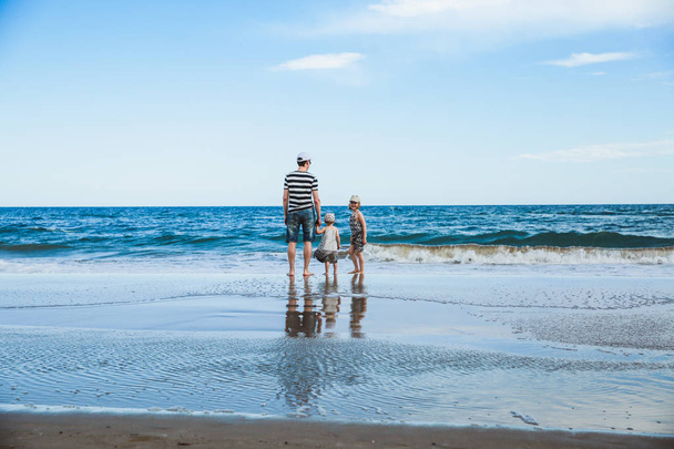 padre y dos hijas de pie en la playa, el mar Mediterráneo
 - Foto, Imagen
