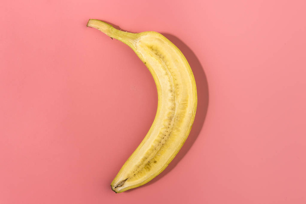 Banana sliced on pastel pink background. Minimal fruit concept. Caontrast shadows  - Foto, immagini