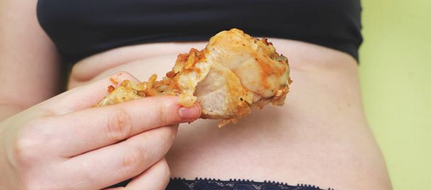 Kövér nő a gazdaság, és eszik sült csirke. élelmiszer- és egészségügyi koncepció - Fotó, kép