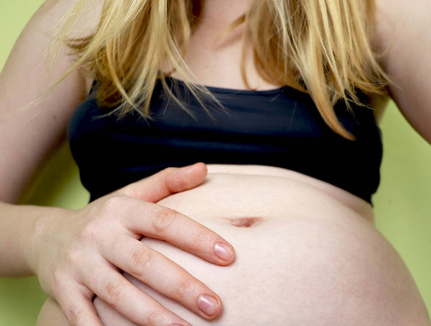 Νεαρή έγκυος γυναίκα, στον πόνο με τη συστολή εργασίας, κάθεται στο κρεβάτι στο υπνοδωμάτιο, ετοιμάζεται να γεννήσει ένα - Φωτογραφία, εικόνα