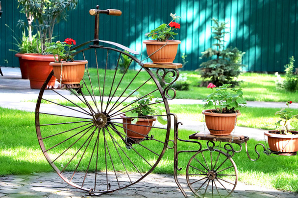 Ένα παλιό ποδήλατο με καλάθια λουλουδιών για τη διακόσμηση πάρκων και κήπων. - Φωτογραφία, εικόνα