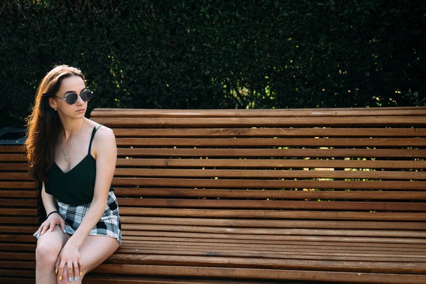 joven chica posando en verde parque escena sentado en banco
 - Foto, Imagen