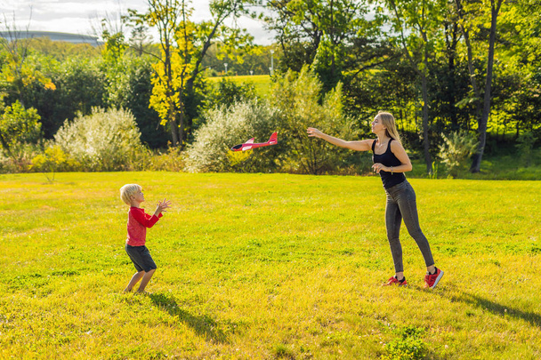 Mother and son playing with a large model toy aeroplane in the park. - 写真・画像