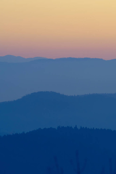 Warstwy sylwetek Hills w kolory Zmierzch i pomarańczowe niebo po zachodzie słońca w Słowenii. Turystyka, piesze wycieczki, sprzęt do koncepcji natury, środowiska i leśnictwa. - Zdjęcie, obraz