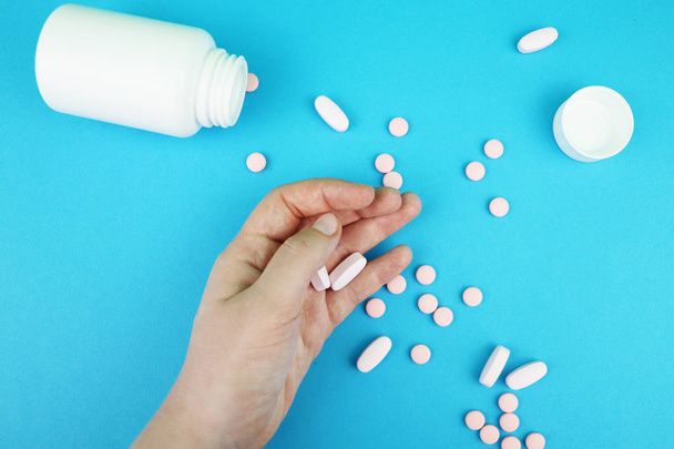 Comprimidos e medicamentos na mão sobre um fundo azul
 - Foto, Imagem