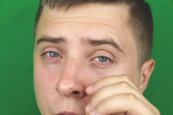 Δάκρυα στα μάτια του κλάμα ενήλικα άνθρωπο. Πράσινο φόντο. Chromakey - Φωτογραφία, εικόνα