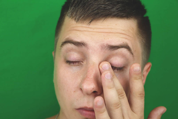 Tränen in den Augen eines weinenden erwachsenen Mannes. Grüner Hintergrund. chromakey - Foto, Bild