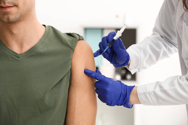 Médico vacinando paciente masculino na clínica
 - Foto, Imagem