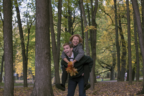 Happy young couple playing with fallen leaves in autumn park - Foto, immagini